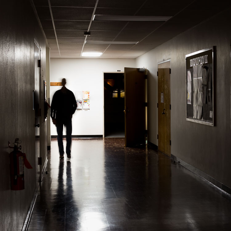 long exposure of man walking down dark hallway