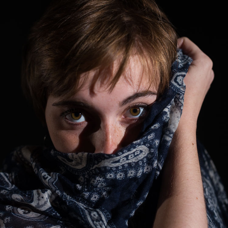 Posed image of woman covering her mouth with a shawl
